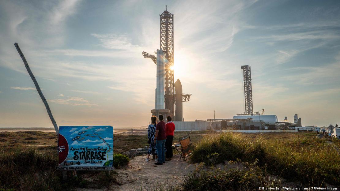 Pessoas observam foguete em plataforma de lançamento