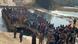 Royal Thai Army officials stand beside hundred of people waiting on a large boat on a river Royal Thai Army officials stand beside hundred of people waiting on a large boat on a river