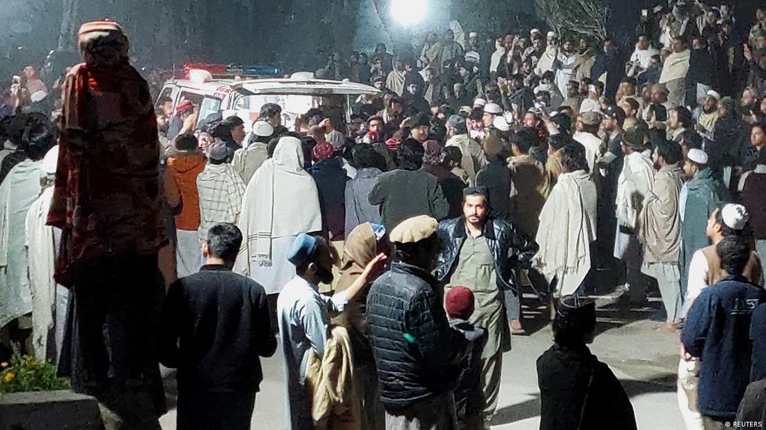 La gente se reúne cerca de una ambulancia fuera de un hospital, después de un atentado suicida en Bannu, Pakistán.