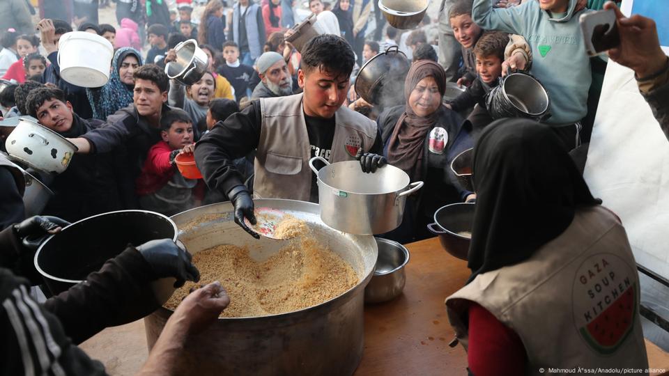 Distribución de comida en la Franja de Gaza: un joven reparte comida en ollas y otros recipientos a los habitantes de Gaza (4.03.2025). Distribución de comida en la Franja de Gaza: un joven reparte comida en ollas y otros recipientos a los habitantes de Gaza (4.03.2025).