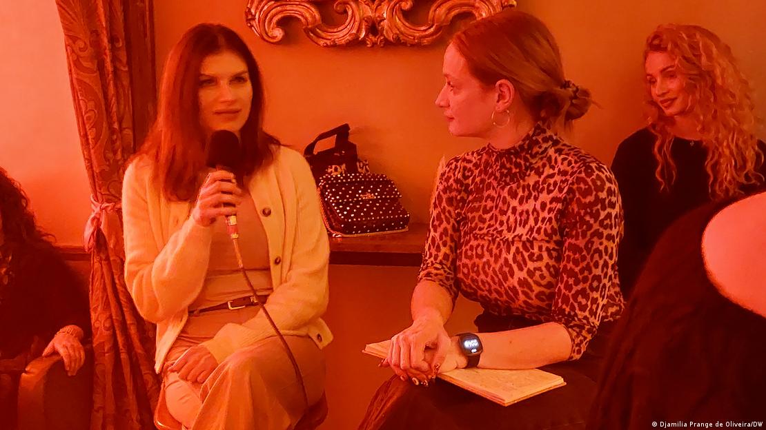 Linda Loran spricht ins Mikrofon, während Alina Kuhl aufmerksam zuhört Linda Loran spricht ins Mikrofon, während Alina Kuhl aufmerksam zuhört