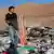 Un hombre sostiene una vieja bandera estadounidense entre los desechos textiles acumulados en el desierto de Atacama.