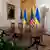 Table with four chairs, US and Ukrainian flags in background