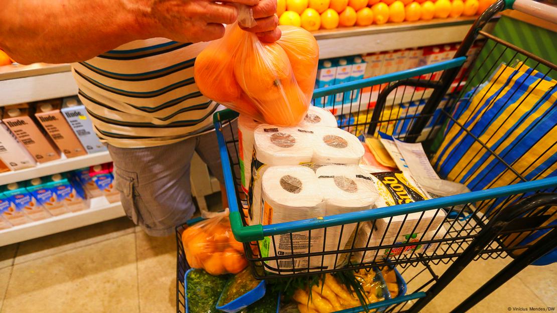 Homem coloca laranjas em carrinho de supermercado 