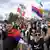 Students and anti-government protesters wearing or carrying flags and banners cheer and blow whistles as they walk along a tree-lined country road on their way to Belgrade, Cortanovci, Serbia, March 13, 2025