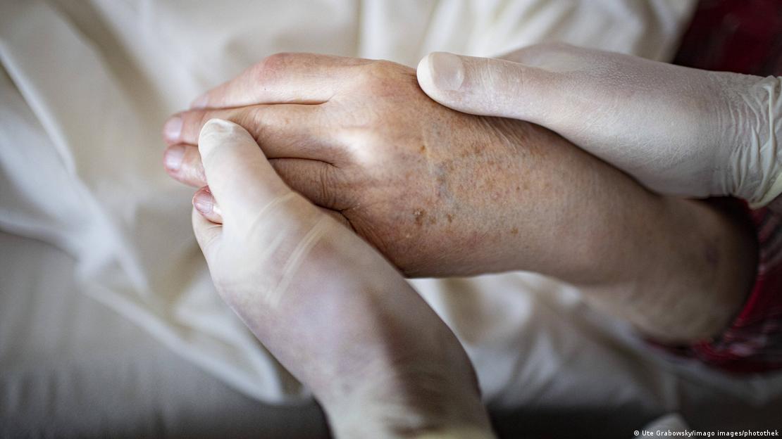 ایک نرس ایک مریض کا ہاتھ پکڑے ہوئے