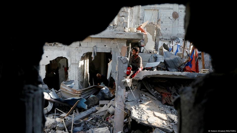 Familias palestinas revisan las ruinas tras el bombardeo israelí de la noche en Jan Yunis. Un niño contempla el panorama sentado sobre las ruinas.