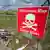 A red warning sign to the right of the picture taken in Ukraine alerts locals to the danger of mines 