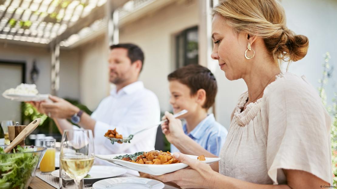 Dois adultos e uma criança comendo juntos.