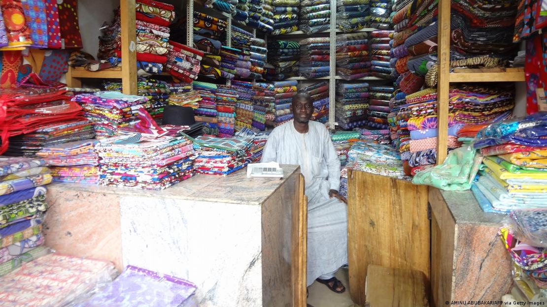 A textile seller sits surrounded by his wares in a shop in Kano, FILE 2015 A textile seller sits surrounded by his wares in a shop in Kano, FILE 2015