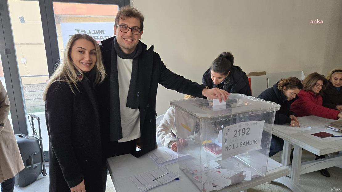 El acompañante de Dilek Imamoglu introduce sonriente su papeleta en una urna en un centro de votación del CHP establecido para elegir su candidato presidencial, con la única postulación de Ekrem Imamoglu, este domingo por la mañana. 