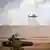 Ormanlık bir alanda askeri tatbikata katılan tank ve iki helikopter