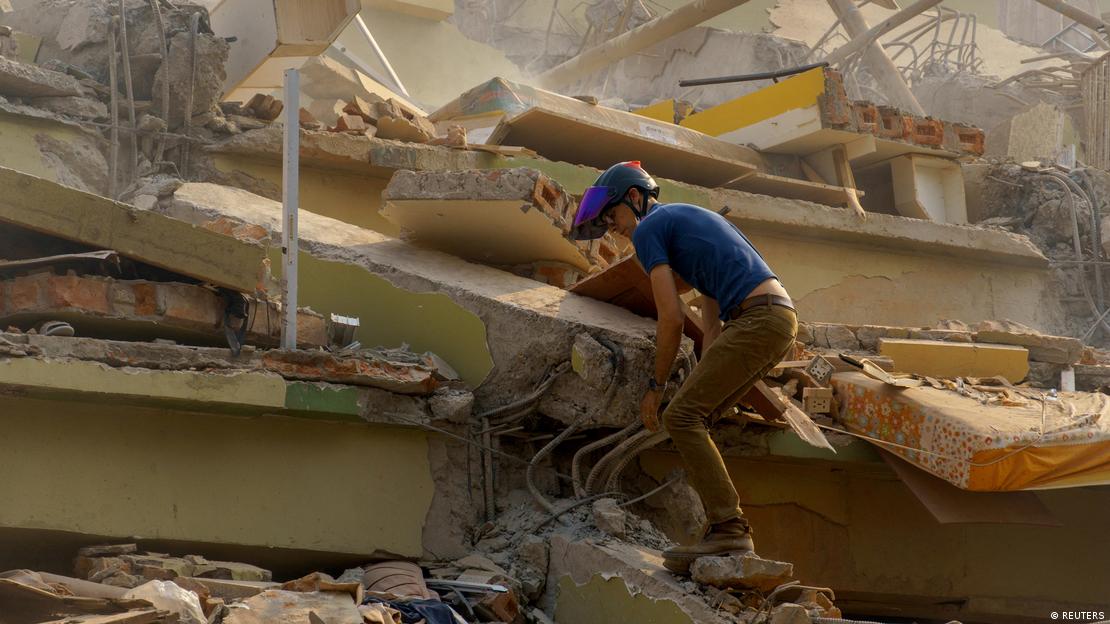 Civil com capacete caminha sobre escombros de prédio tombado por terremoto em Mianmar Civil com capacete caminha sobre escombros de prédio tombado por terremoto em Mianmar