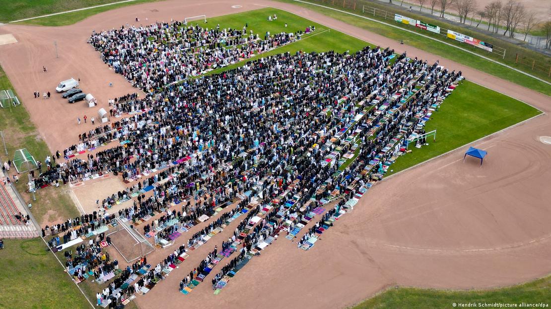 Dron ile havaden çekilmiş bu görselde, namaz için bir futbol sahasında toplanan binlerce Müslüman düzenli saflar hâlinde görülüyor