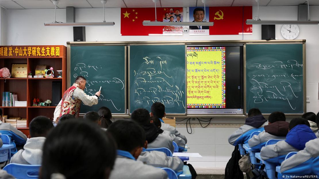 Students in school uniforms at a Tibetan middle school in the city of Nyingchi learn the Tibetan language. Hanging in the classroom are the Chinese national flag, the flag of the Communist Party, a portrait of President Xi Jinping, and photos of past CCP leadership generations Students in school uniforms at a Tibetan middle school in the city of Nyingchi learn the Tibetan language. Hanging in the classroom are the Chinese national flag, the flag of the Communist Party, a portrait of President Xi Jinping, and photos of past CCP leadership generations