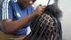 A black woman's hair is braided in a salon. A black woman's hair is braided in a salon.