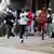 People run as riot police officers clash with protesters in the Zimbabwean capital, Harare, March 31, 2025