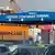 Cars are parked and trucks with containers stand in line at the entrance to Gdynia Container Terminal in Gdynia, Poland. In the background is a large crane