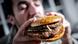 Młody mężczyzna jedzący podwójnego hamburgera Młody mężczyzna jedzący podwójnego hamburgera