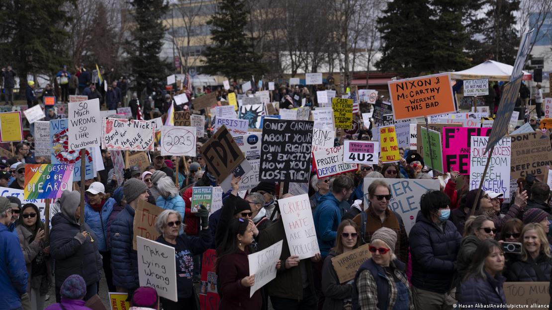 En el centro de Anchorage, Alaska, la multitud coreó consignas y ondeó pancartas para expresar su oposición a los recortes y despidos del Departamento de Eficiencia Gubernamental (DOGE), las deportaciones de inmigrantes y las políticas estadounidenses sobre Gaza. En el centro de Anchorage, Alaska, la multitud coreó consignas y ondeó pancartas para expresar su oposición a los recortes y despidos del Departamento de Eficiencia Gubernamental (DOGE), las deportaciones de inmigrantes y las políticas estadounidenses sobre Gaza.