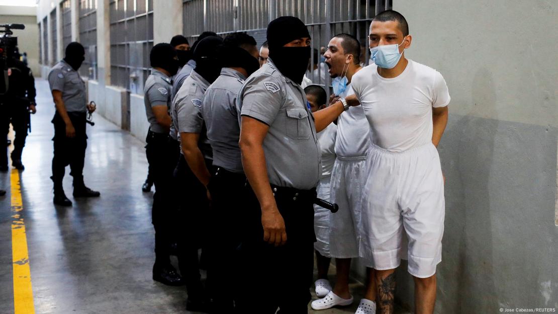 El Salvador'un Tecoluca kentindeki Terörist Tutukevi (CECOT) hapishanesinde düzenlenen medya turu sırasında hapishane gardiyanları mahkumları güvenlik altına alıyor.