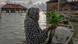 Pasijah holds mangrove seedlings as she sits in a boat in the submerged hamlet of Rejosari Senik, Demak regency. Pasijah holds mangrove seedlings as she sits in a boat in the submerged hamlet of Rejosari Senik, Demak regency.