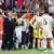 Antonio Rüdiger is restrained by a coach as he looks on to the ptich surrounded by teammates and coach Carlo Ancelotti
