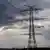 Açık alanda, üzerinde elektrik kabloları bulunan bir enerji nakil hattı direği görülüyor.