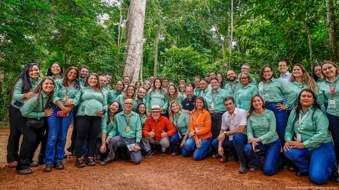 De camisa vermelha e chapéu, o presidente Luiz Inácio Lula da Silva aparece agachado em meio a grupo de funcionários da Vale em Parauapebas, com floresta ao fundo. De camisa vermelha e chapéu, o presidente Luiz Inácio Lula da Silva aparece agachado em meio a grupo de funcionários da Vale em Parauapebas, com floresta ao fundo.