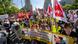 People walk down a street in Berlin holding flags from various trade unions. People walk down a street in Berlin holding flags from various trade unions.