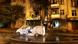 Ein brennendes Wohnhaus und ein bereits ausgebranntes Auto auf einer Straße in Charkiw