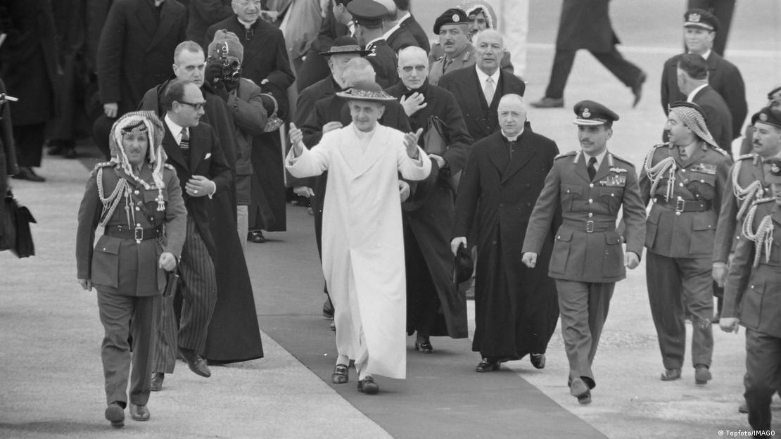 Jordanien Amman 1964 | Papst Paul VI. begrüßt Anhänger am Flughafen Amman beom Empfang durch König Hussein - er geht begleitet von mehreren Personen über einen Teppich auf dem Rollfeld