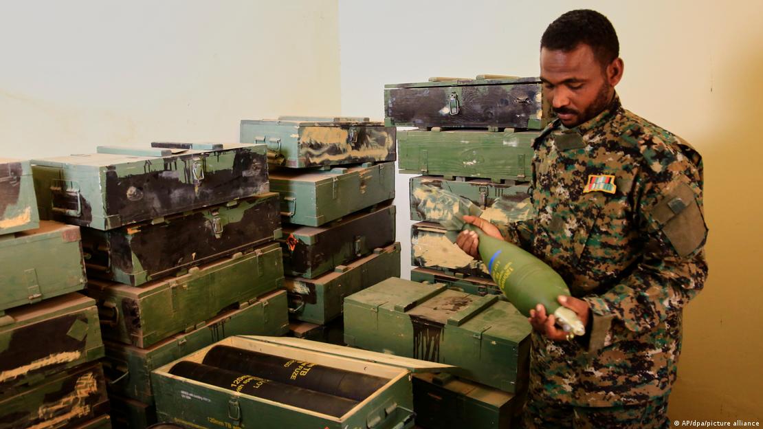 رجل يرتدي زيًا عسكريًا يتفقد الأسلحة