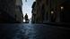 A man pulls his belongings in a trolley behind him, walking along a dark street A man pulls his belongings in a trolley behind him, walking along a dark street