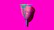 A picture of a pink and blue menstrual cup against a bright pink backdrop A picture of a pink and blue menstrual cup against a bright pink backdrop