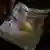 A hand holds a piece of newspaper that is covered in gold dust