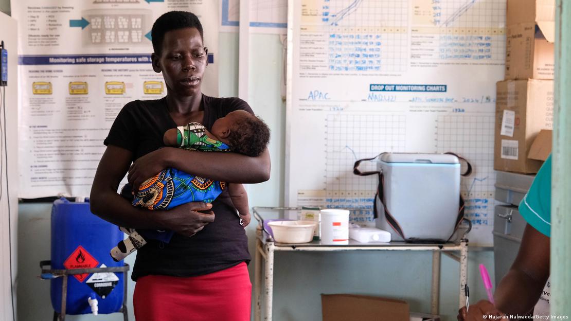Mulher leva bebê para vacinar em Uganda