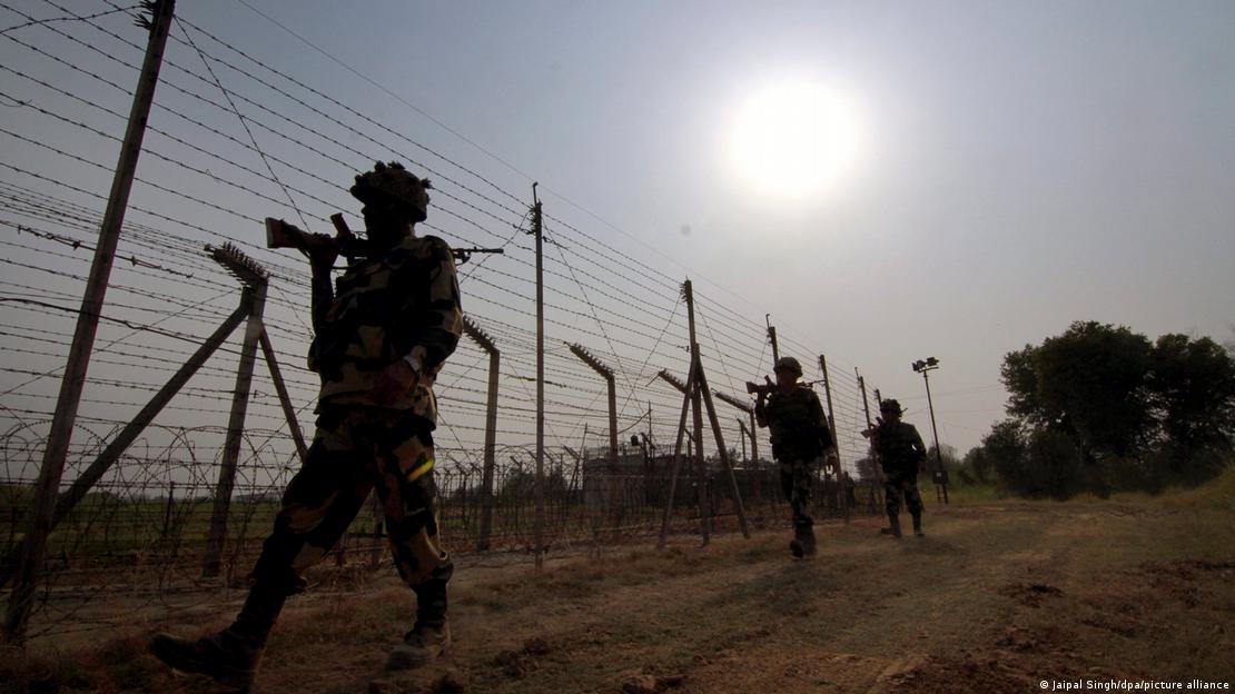 پاک بھارت سرحد پر لگی خار دار تاریں اور وہاں بھارتی علاقے میں گشت کرتے بارڈر سکیورٹی فورس کے اہلکار 