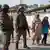 Une femme et une fille en train de marcher à côté de militaires