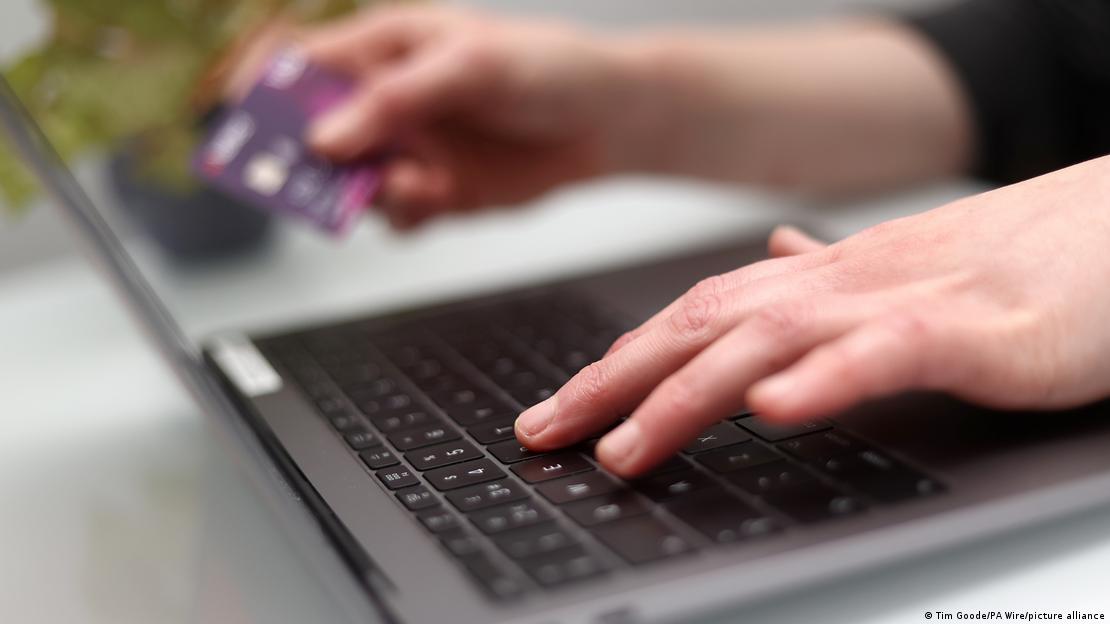 Bir internet kullanıcıso, diz üstü bilgisayarına, elindeki kredi kartınının bilgilerini giriyor