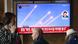 People sit and stand around a large TV screen in South Korea on May 8, 2025, showing missiles fired by North Korea flying across a clear blue sky. People sit and stand around a large TV screen in South Korea on May 8, 2025, showing missiles fired by North Korea flying across a clear blue sky.