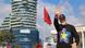 Prime Minister Edi Rama, dressed in a black cap and a black sweater with a yellow star on a blue-black-and-red background, waves to supporters during the opening rally of his party's campaign for the May 11 general election, Tirana, Albania, April 12. An Albanian flag flies in the background