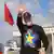 Prime Minister Edi Rama, dressed in a black cap and a black sweater with a yellow star on a blue-black-and-red background, waves to supporters during the opening rally of his party's campaign for the May 11 general election, Tirana, Albania, April 12. An Albanian flag flies in the background