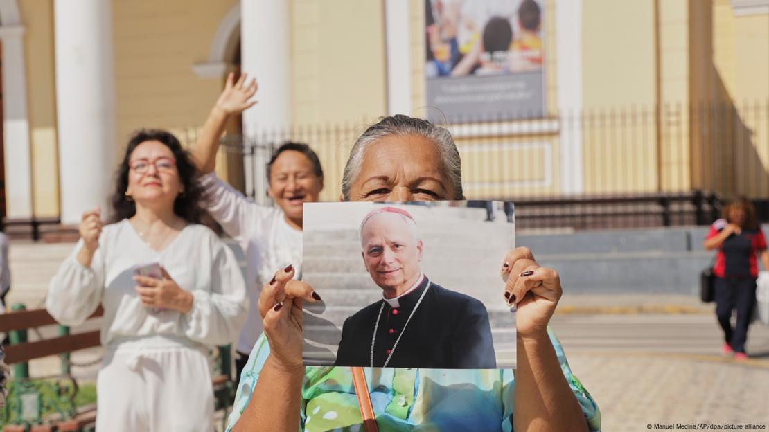 Mulher segura foto do novo papa, com outras fieis atrás