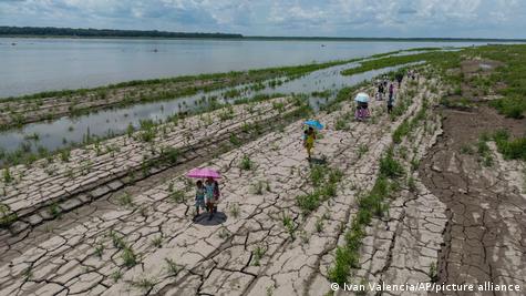 Pessoas caminham no leito seco do rio Amazonas, durante seca de 2024
