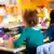 A girl wearing hearing aids sits at a desk in a classroom. She and other pupils are seen from behind