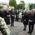 Bundespräsident Frank-Walter Steinmeier, Bundeskanzler Friedrich Merz und Bundestagspräsidentin Julia Klöckner (4.v.r.) stehen vor zwei Blumenkränzen auf dem Friedhof