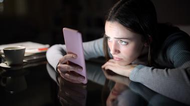 Νεαρή κοιτά με ανησυχία το κινητό της 