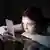 A woman looking at her phone in a dark room