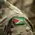 Detalle de la bandera en el hombro del militar, sobre un uniforme de camuflaje.